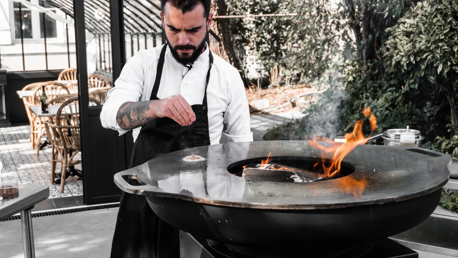 Cuisinier devant un brasero en flammes, sur la terrasse